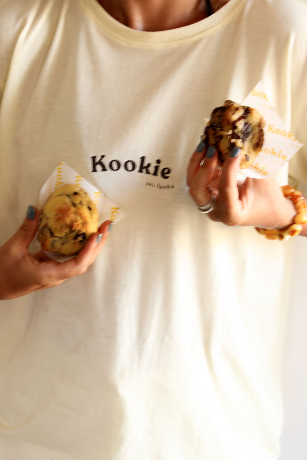 Wearing a cream Kookie t-shirt while holding two cookies